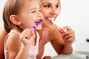 Mãe e filha escovando os dentes