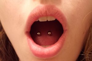 Menina com piercing na lingua
